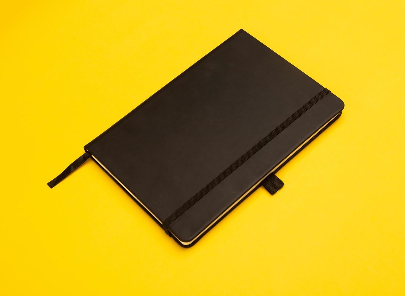 Black notebook isolated on yellow background photo