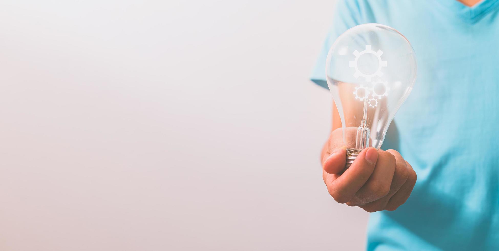 A man holding a light bulb gear symbol photo