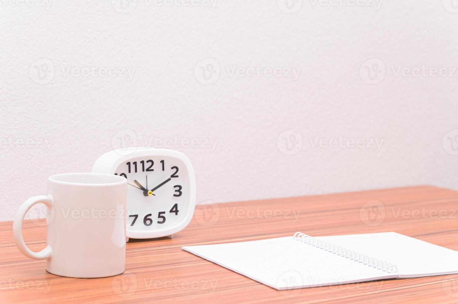 A white mug and a clock on a table photo