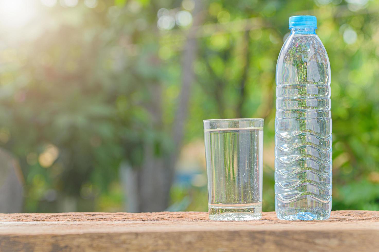 Bottle of drinking water and glass with natural background photo