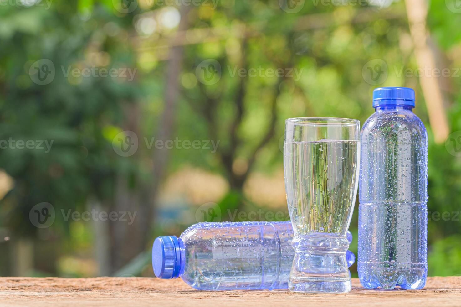 Two plastic bottles with water sitting on a wooden table photo