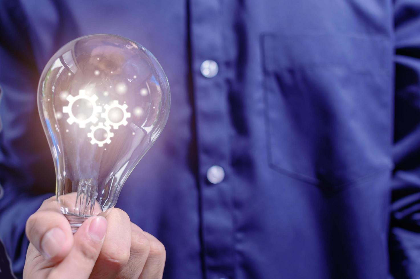 A business man's hand holds a light bulb and has a gear icon photo