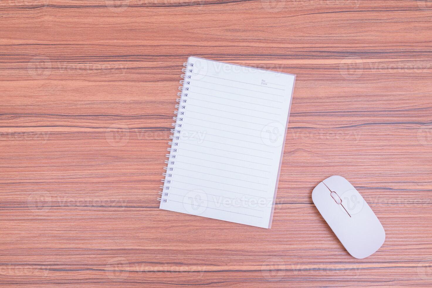 Notebook, mouse and pen on wooden table top view photo
