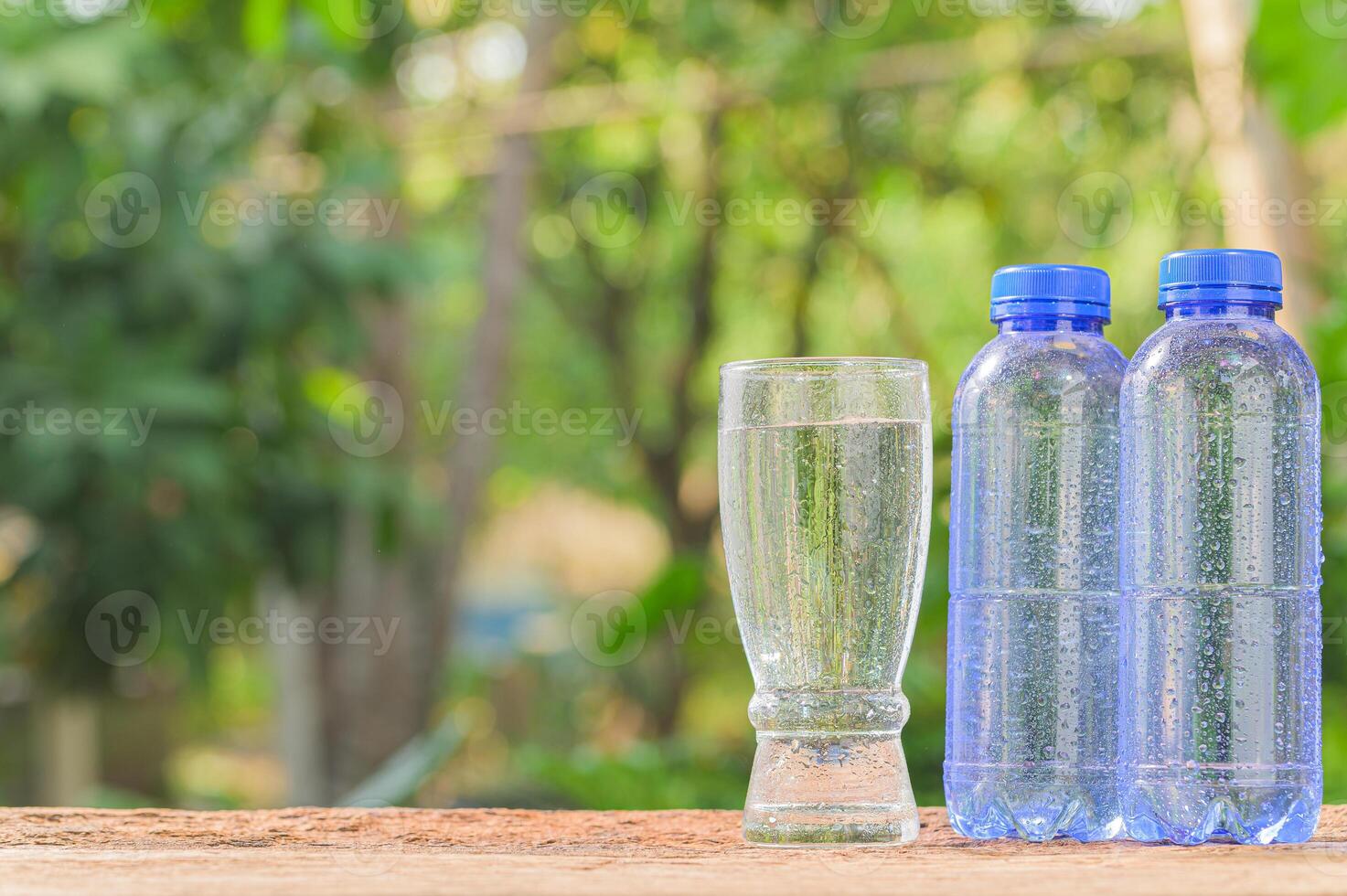 Three plastic bottles and a glass of water on a wooden table photo