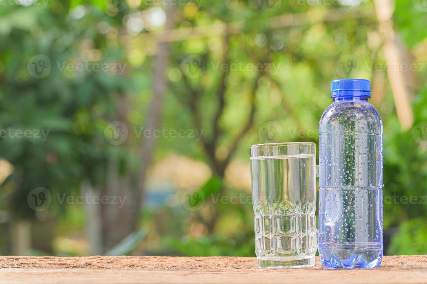 A bottle of water and a glass of water on a wooden table photo