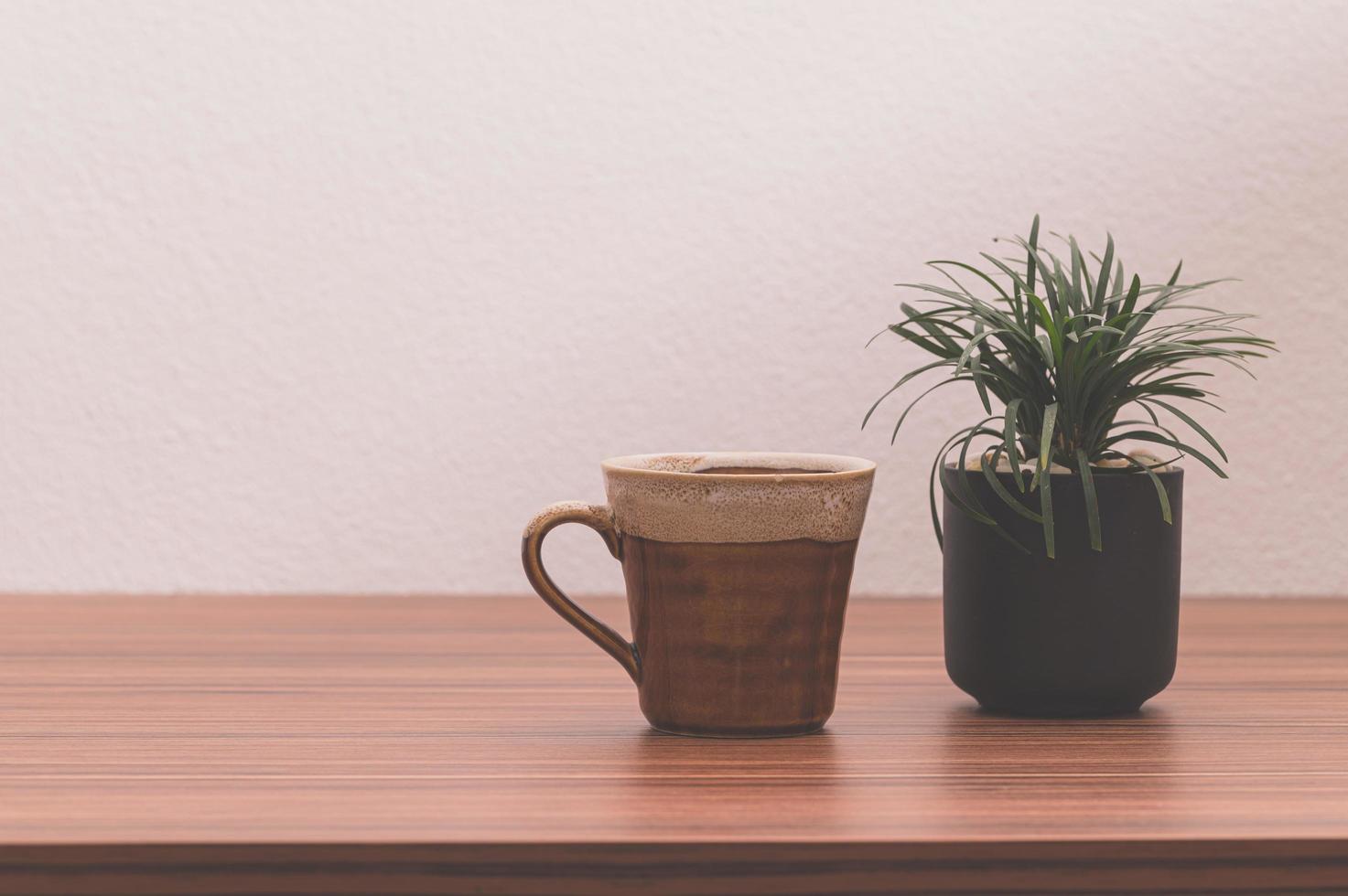 taza de café y planta en maceta sobre la mesa foto