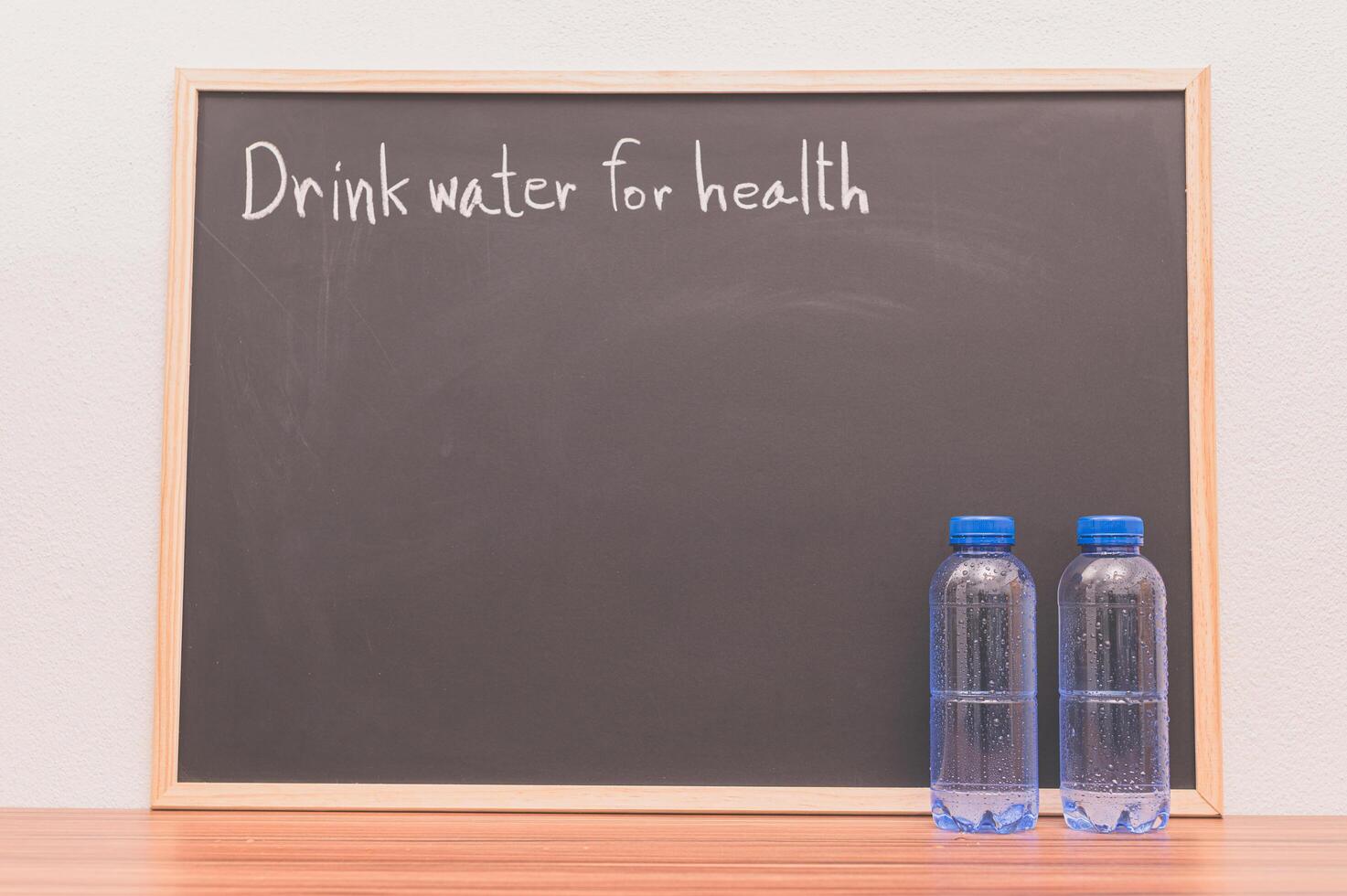 Botellas de agua potable contra la pizarra foto