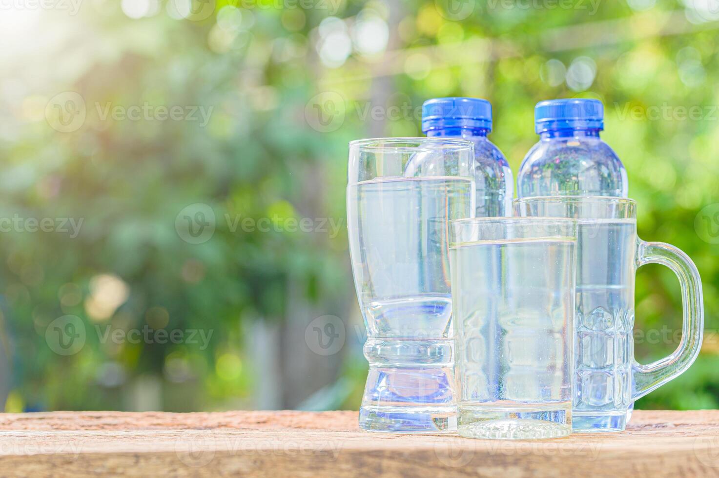 Three bottles of water and two glasses on a wooden table photo