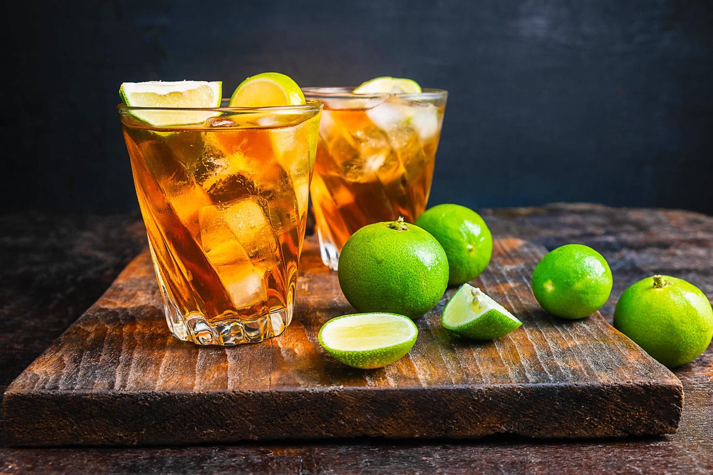 Iced tea and sliced limes on a wood tray on a wooden table photo