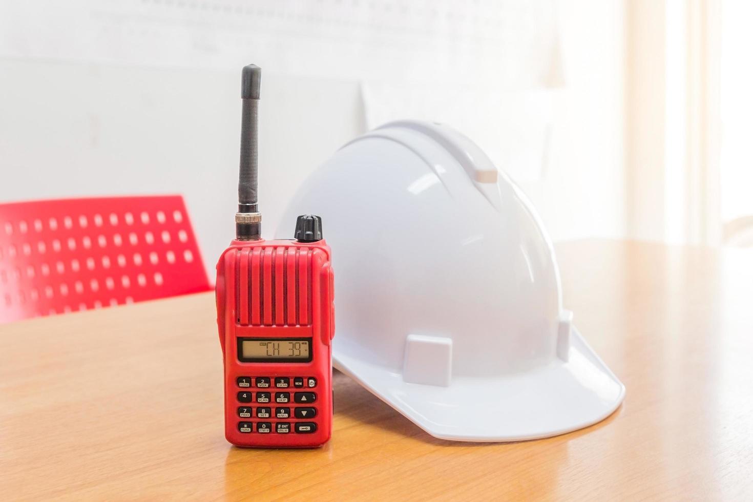 Red walkie-talkie radio and a white safety helmet photo