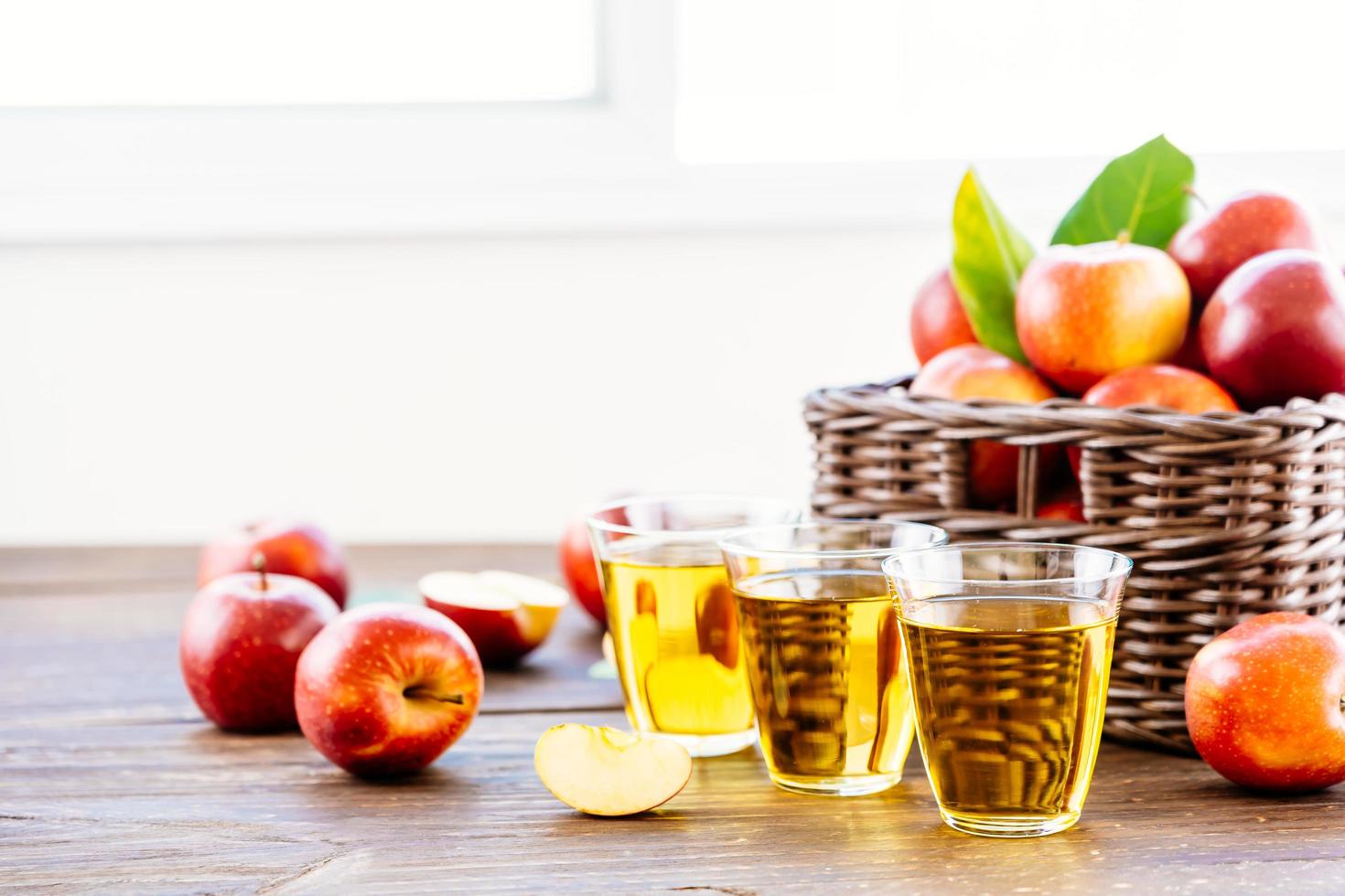 jugo de manzana en vasos y manzanas en la canasta foto