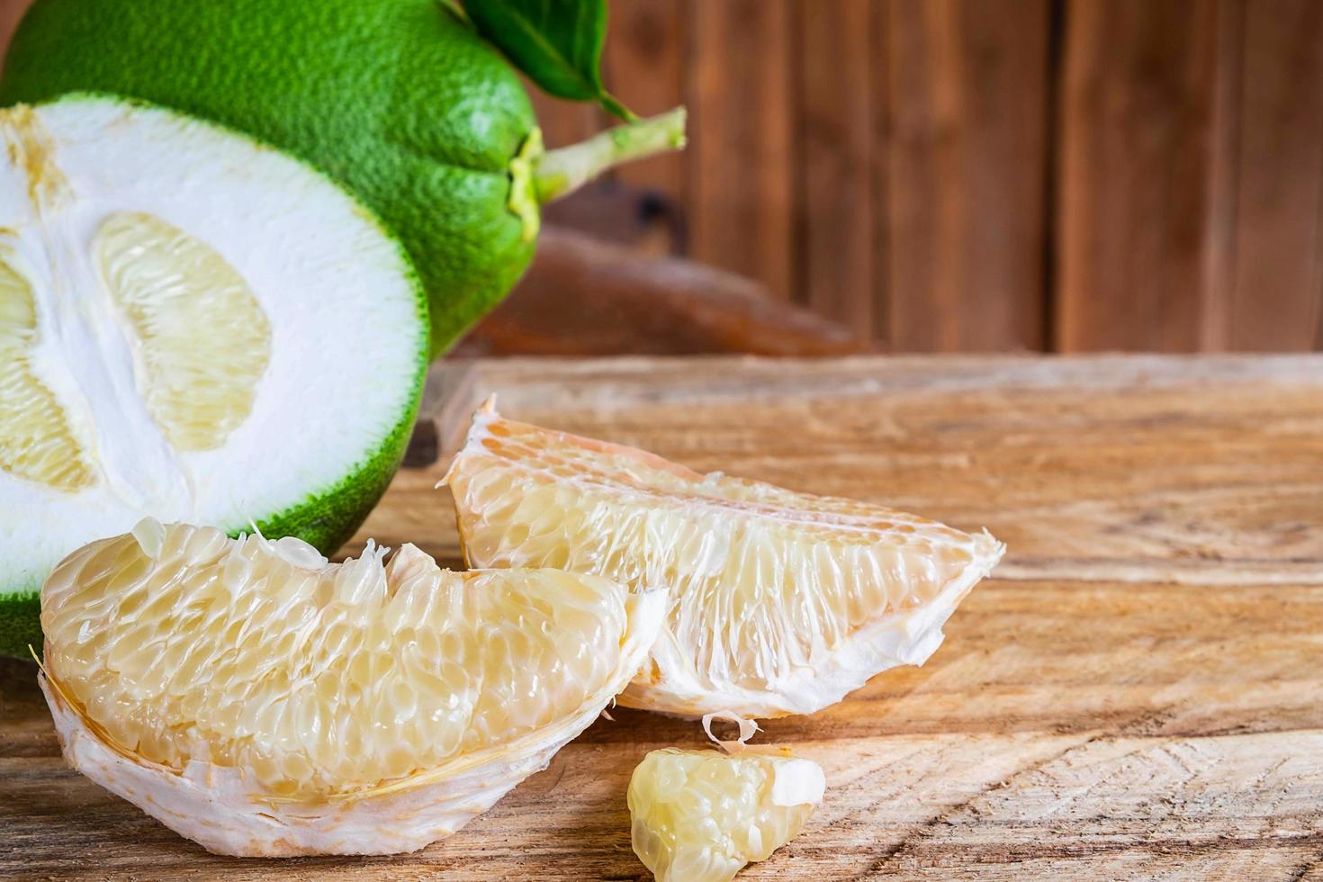 Whole, sliced, and pieces of pomelo fruit on a wooden table photo
