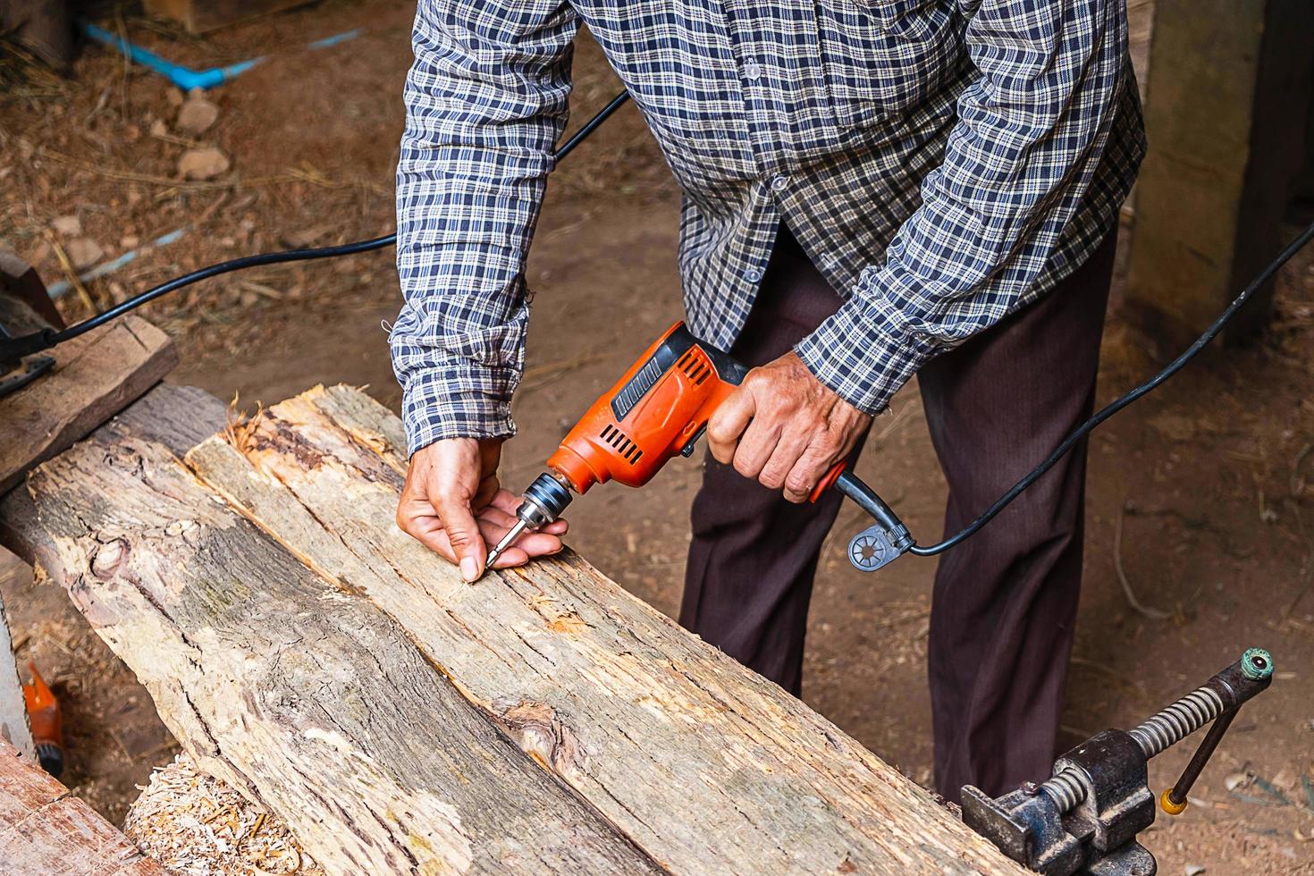 Man using power drill on plank of wood in a woodworking shop photo