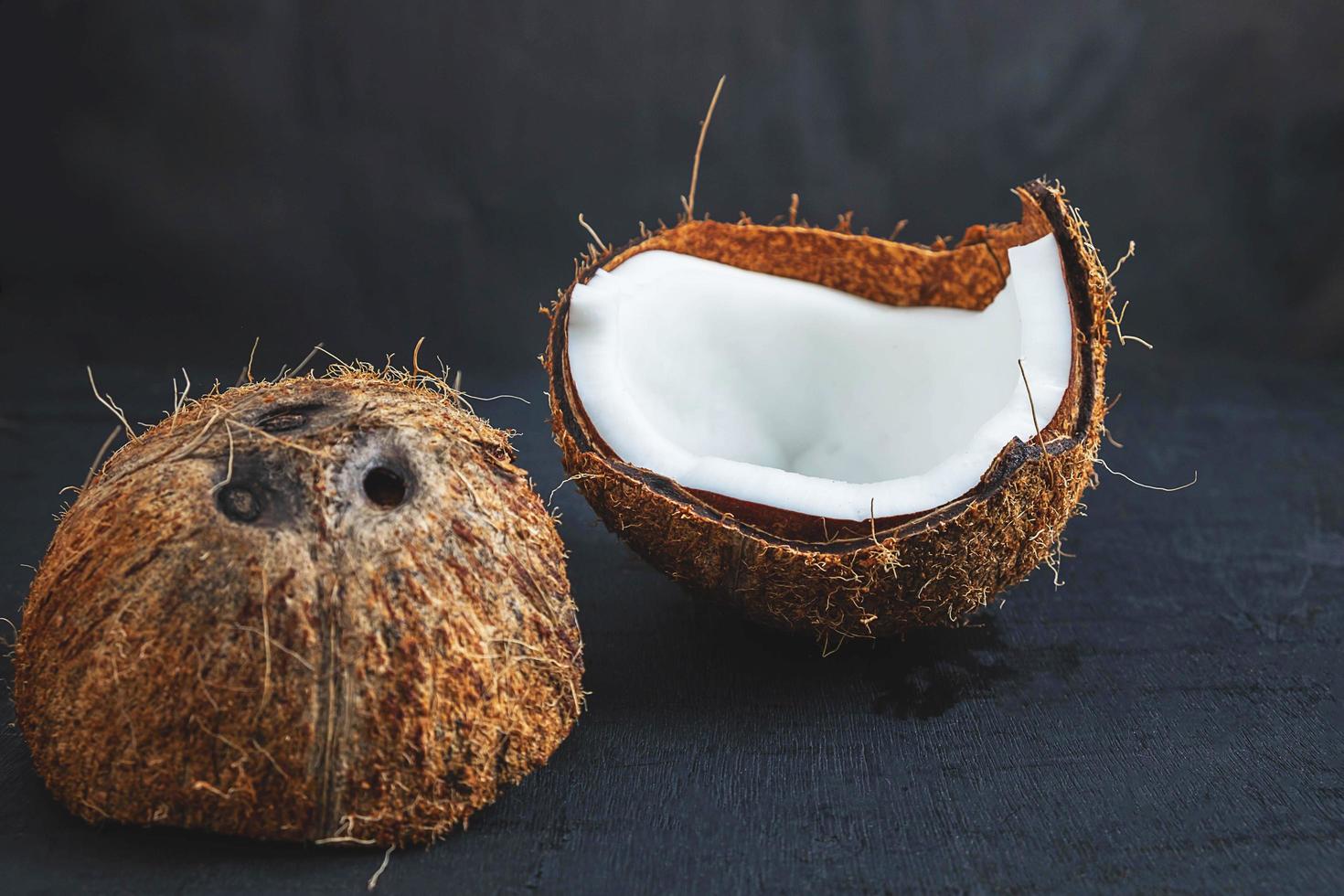 Coconut cut in half on a black table background photo