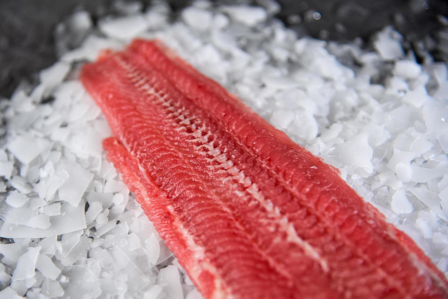 Fresh raw fish steak on ice over dark stone background photo