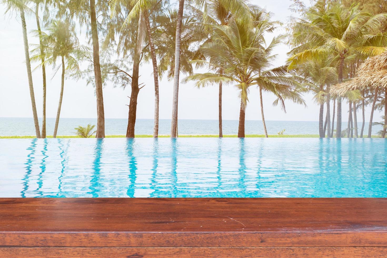 Empty wooden table on a swimming pool with sea background photo