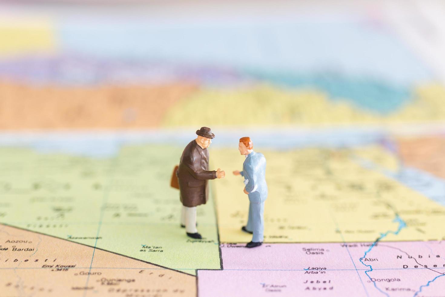 Miniature tourists handshaking on a world map background, journey and travel concept photo