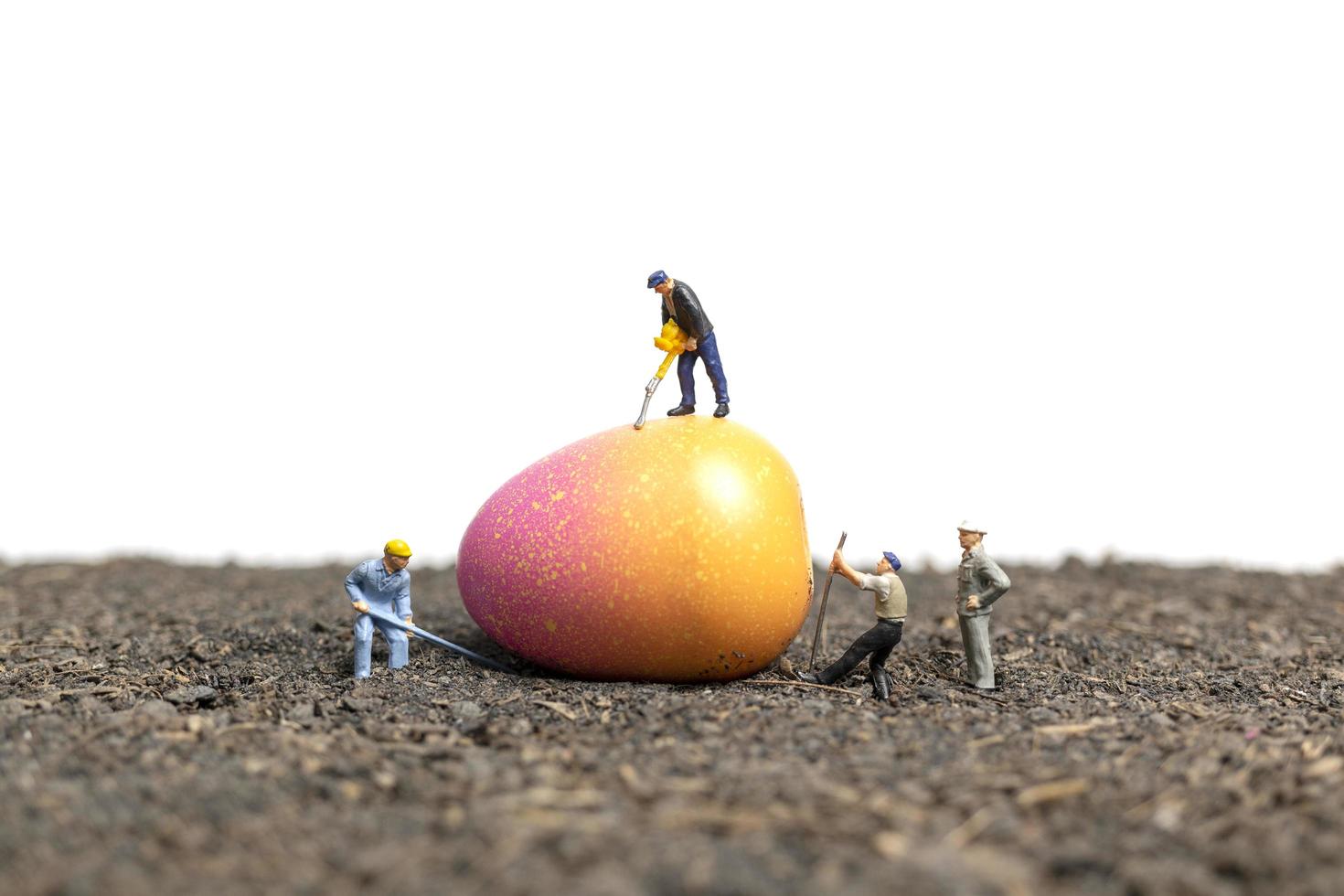 Miniature people working on Easter Eggs for Easter day with a white background photo