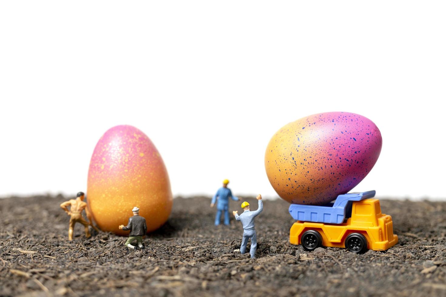 Gente en miniatura trabajando en huevos de pascua para el día de pascua con un fondo blanco. foto