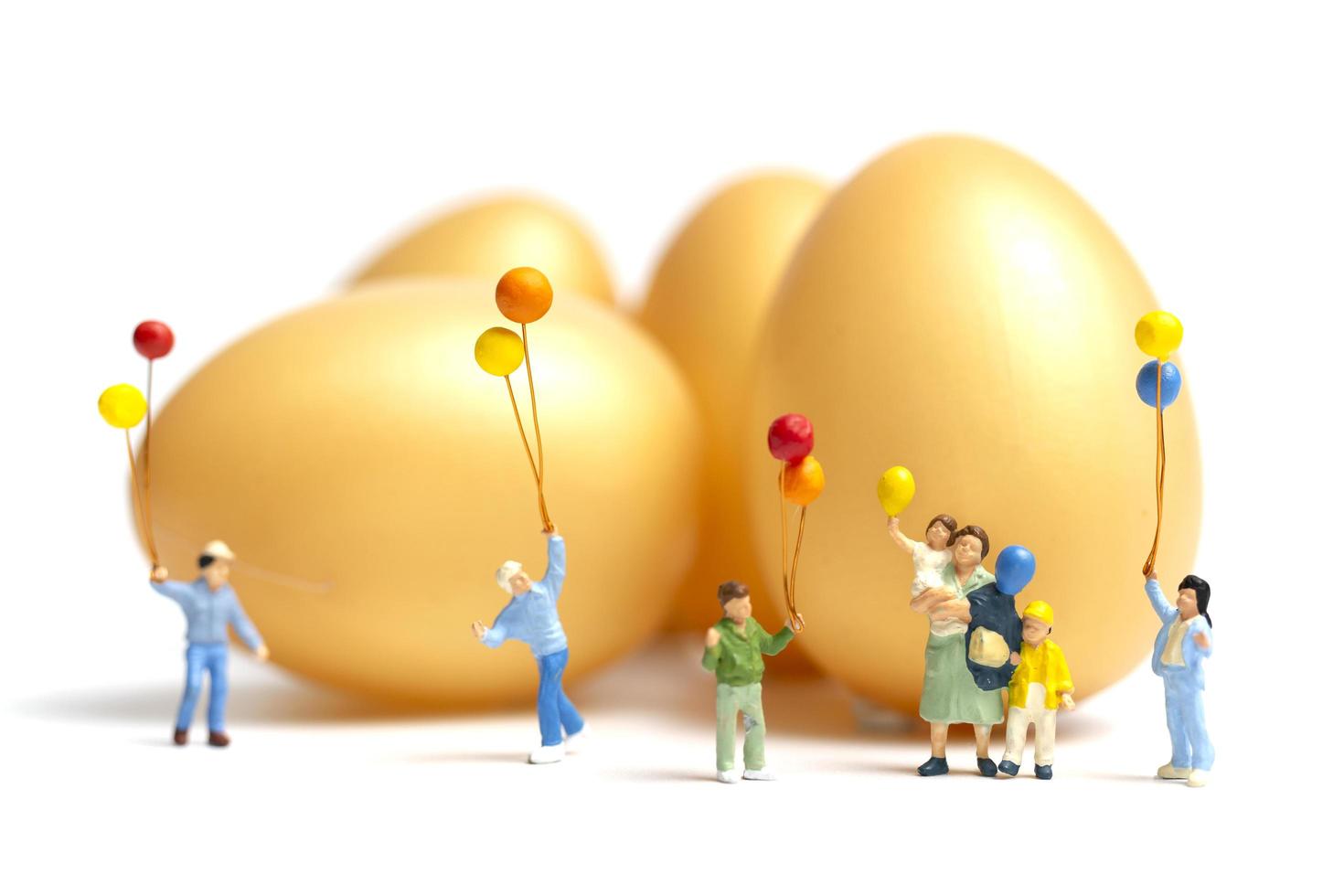 Miniature people holding balloons celebrating Easter on a white background photo