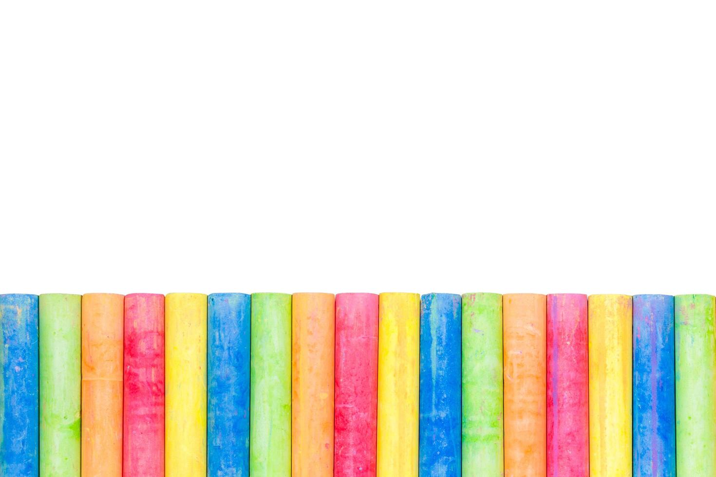 Rows of rainbow-colored chalk isolated on a white background photo