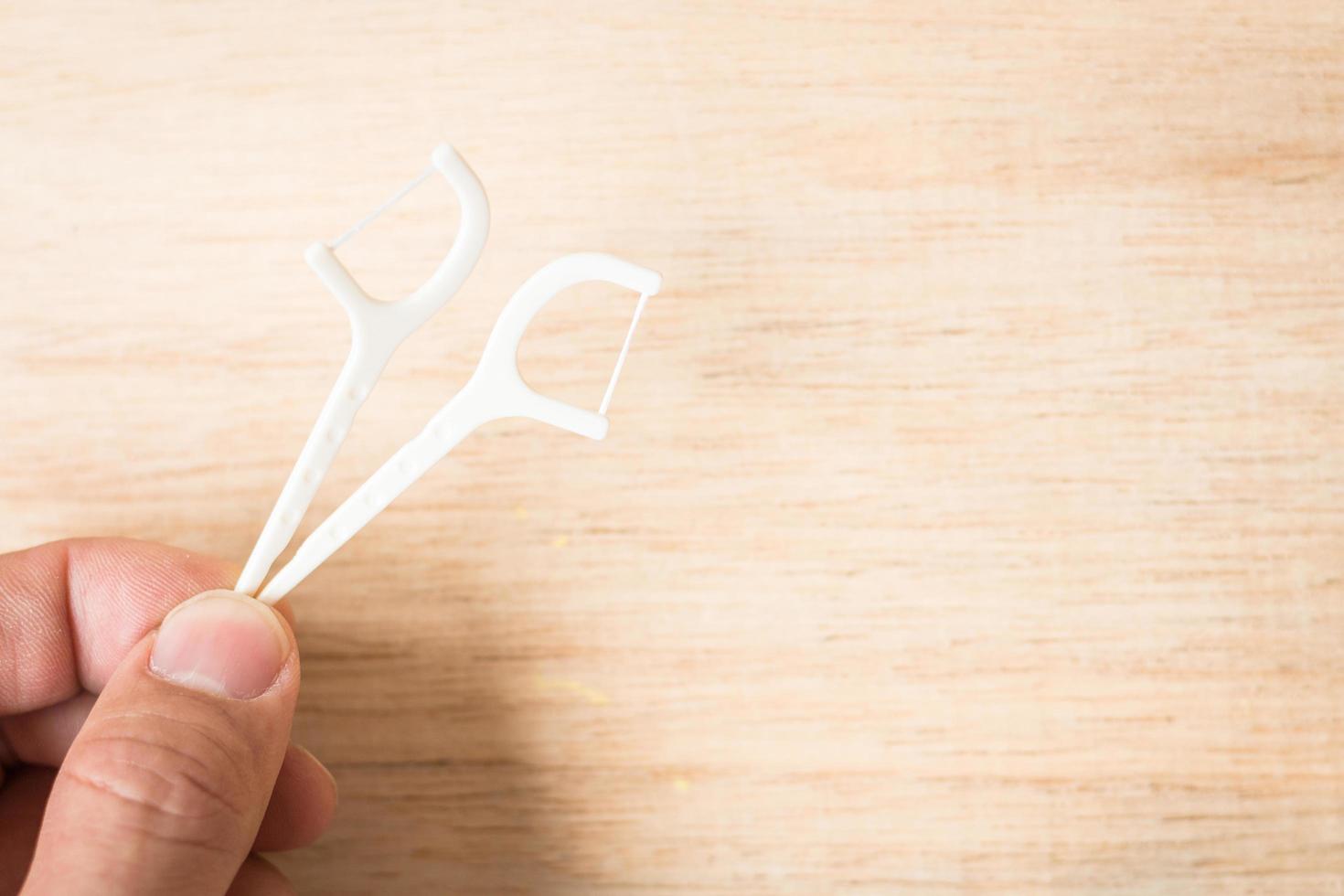 A hand holding an oral device dental flosser on a wooden background photo