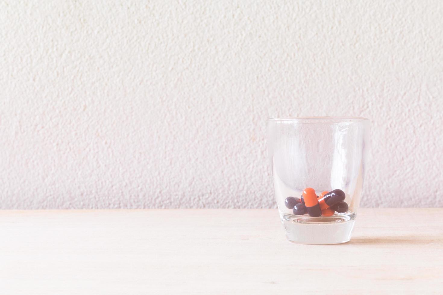 Pill in a glass on a wooden floor and concrete background photo