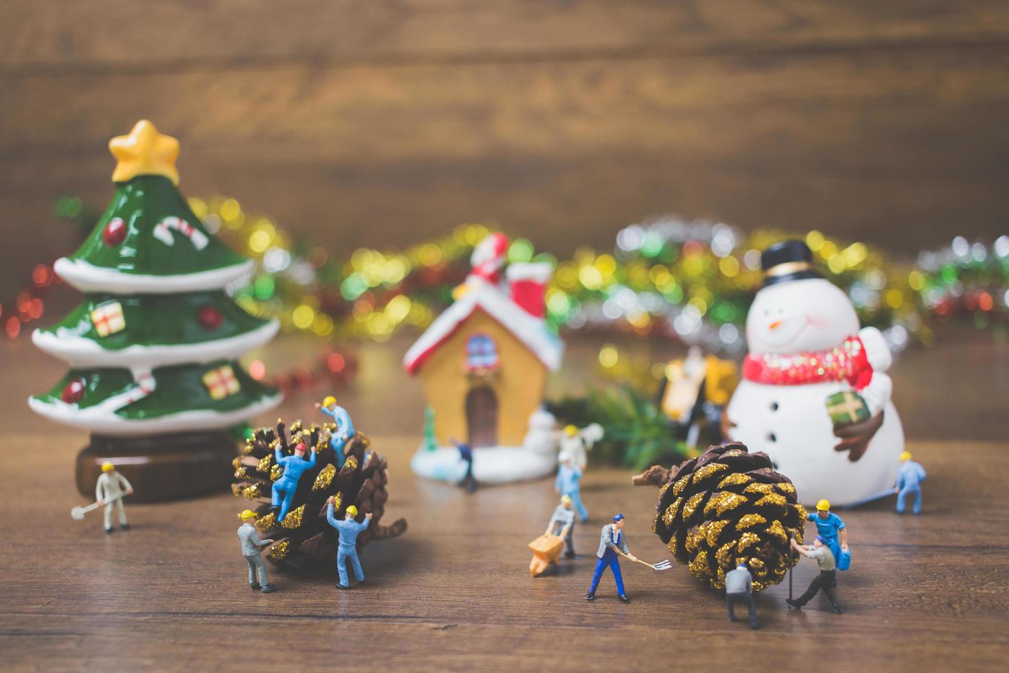 Gente en miniatura creando adornos navideños sobre un fondo de madera foto