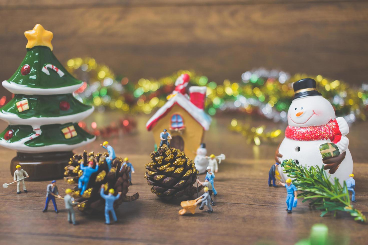 Gente en miniatura creando adornos navideños sobre un fondo de madera foto