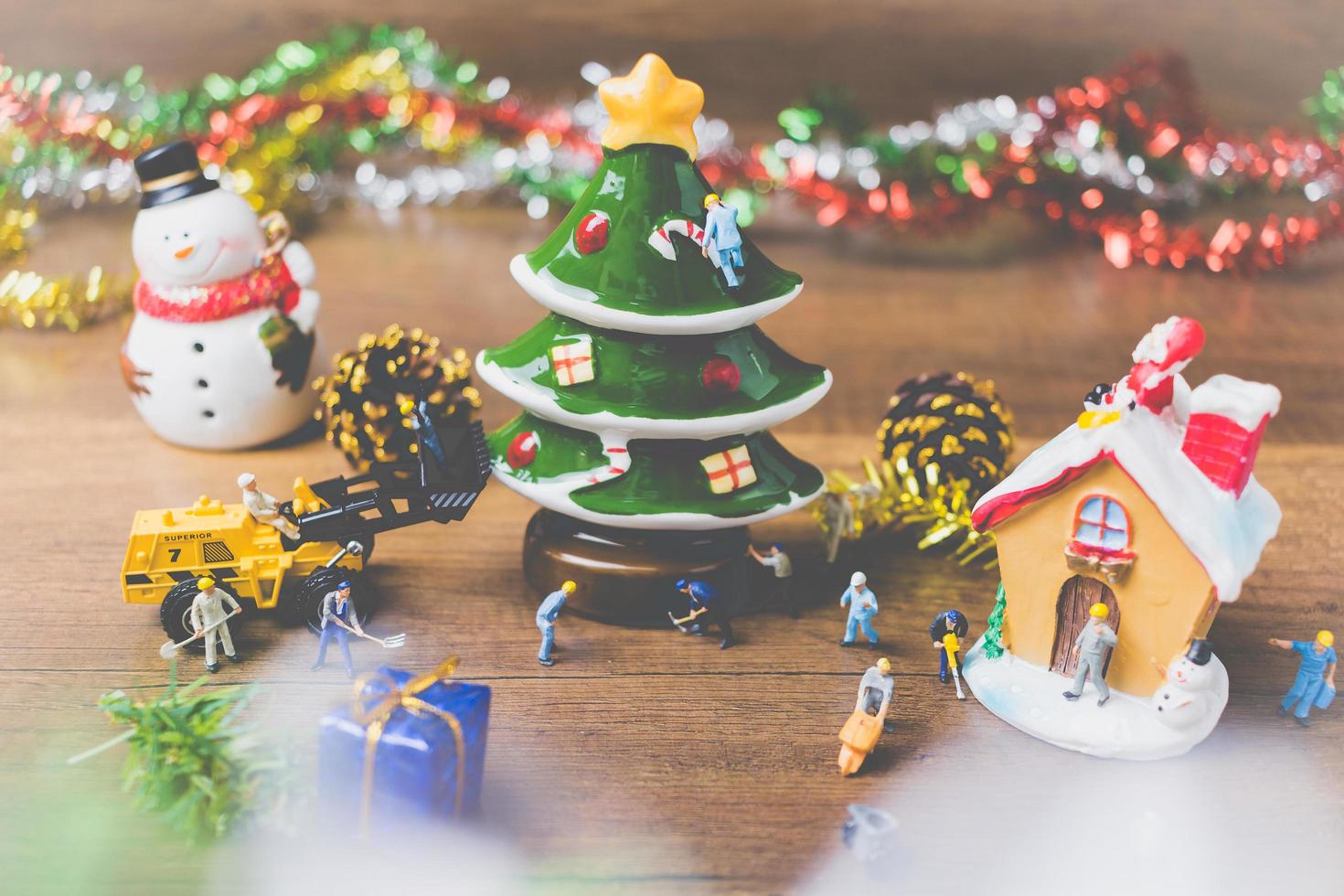 Gente en miniatura creando adornos navideños sobre un fondo de madera foto