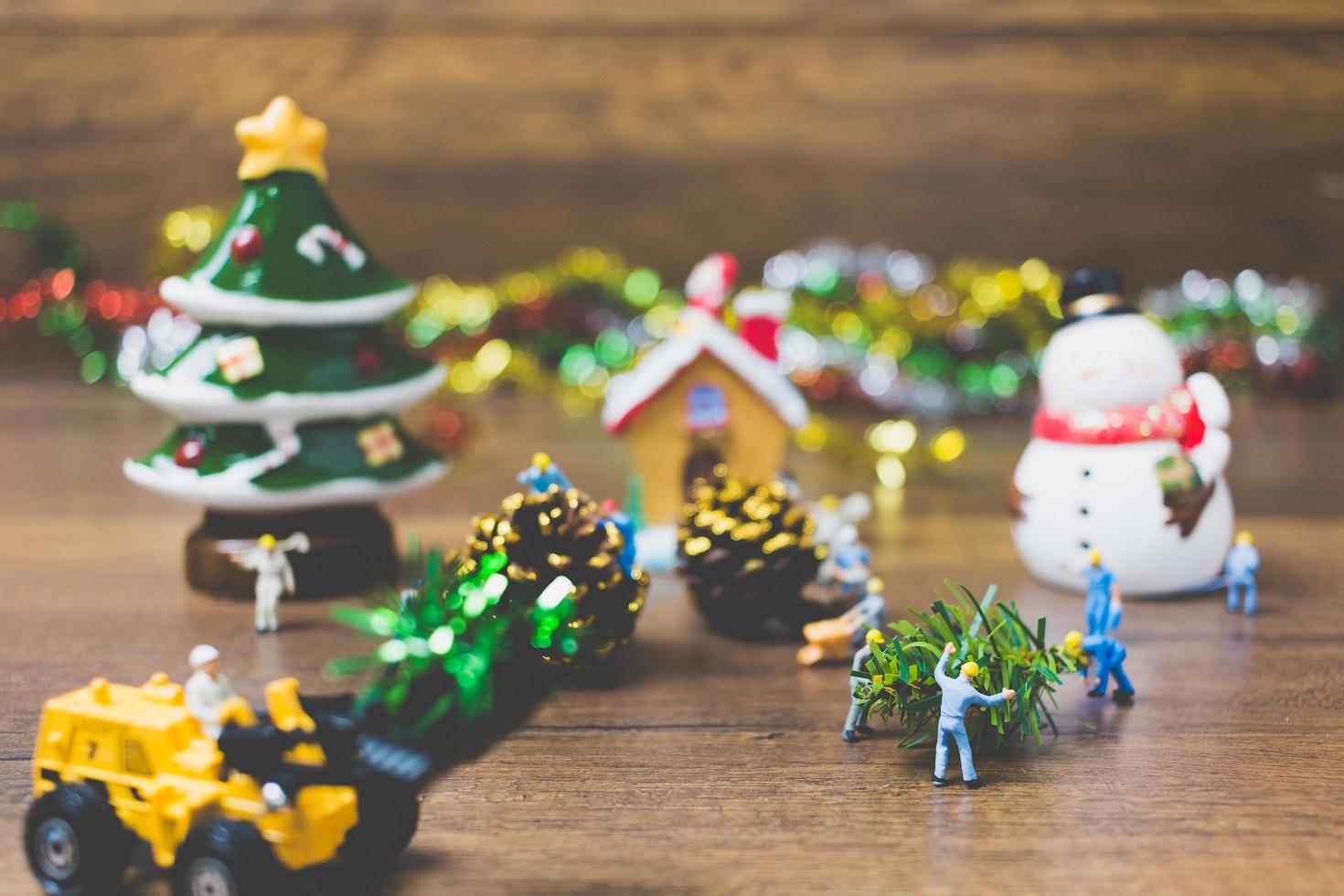 Gente en miniatura creando adornos navideños sobre un fondo de madera foto