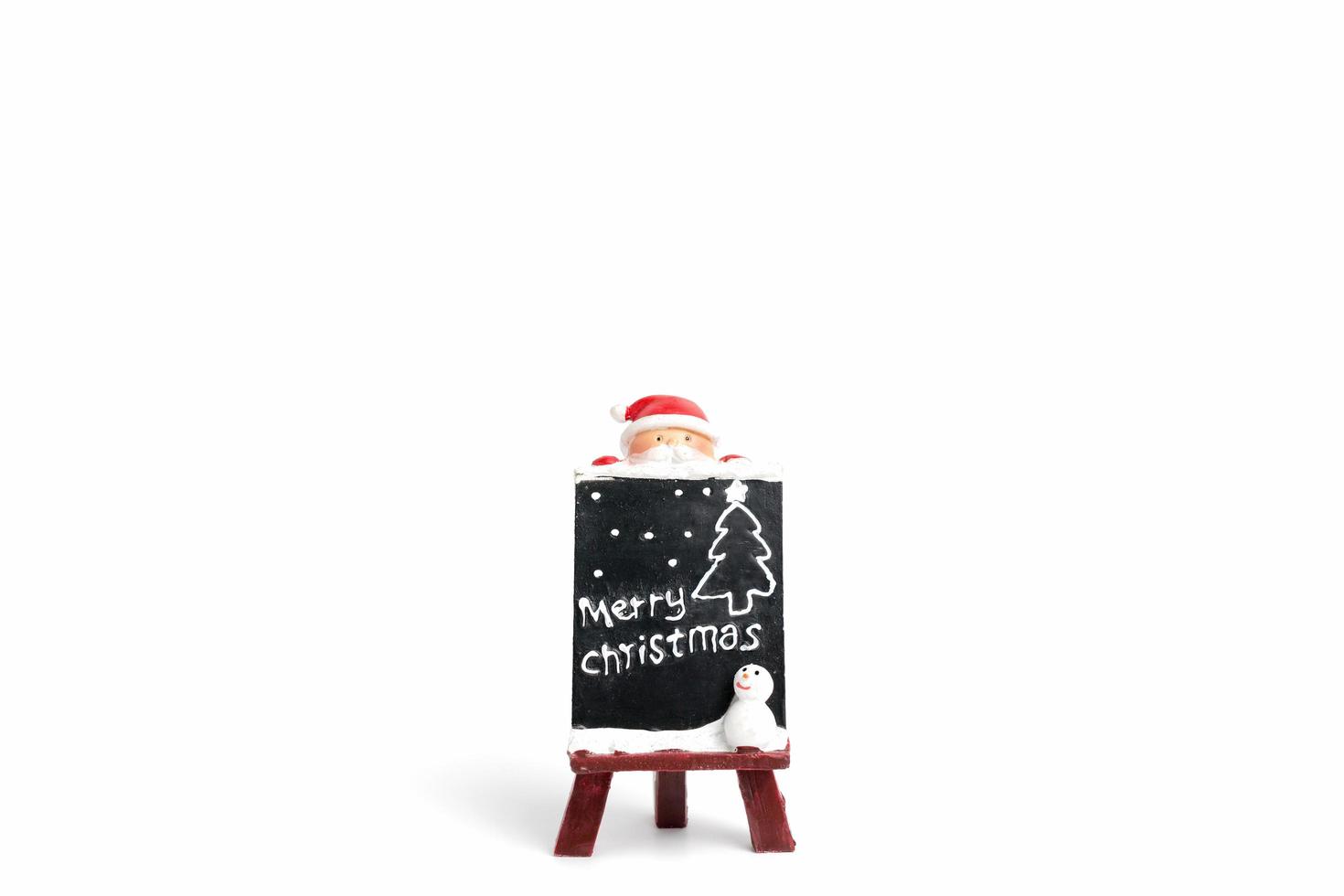 Santa Claus figurine with a miniature chalkboard with Merry Christmas text on a white background photo