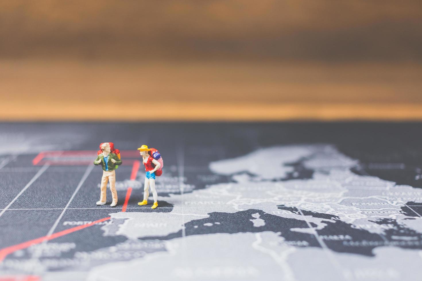 Miniature backpackers walking on a world map, tourism and travel concept photo