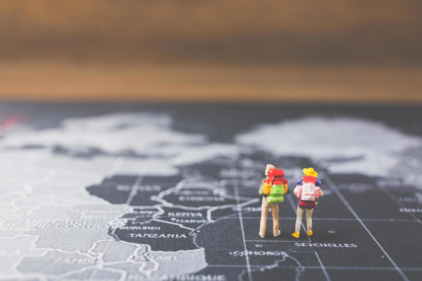 Miniature backpackers walking on a world map, tourism and travel concept photo