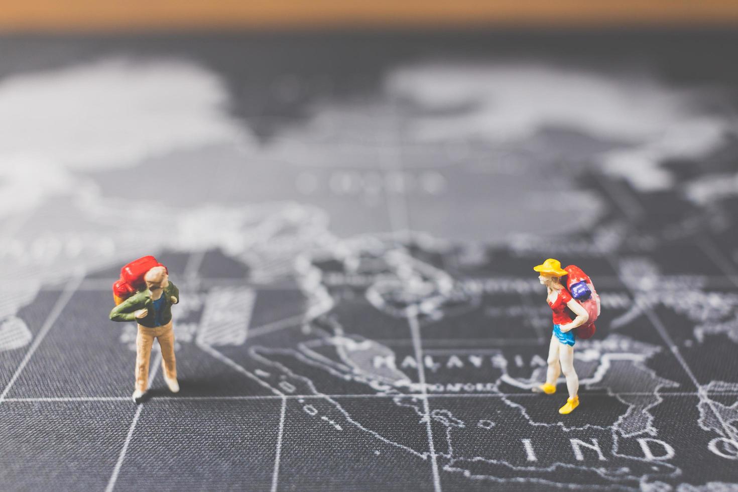 Miniature backpackers walking on a world map, tourism and travel concept photo