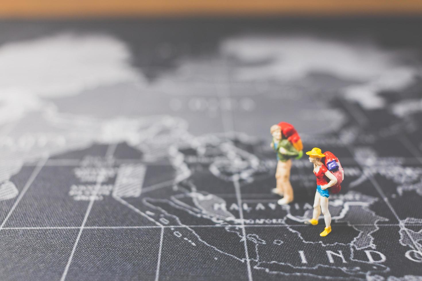 Mochileros en miniatura caminando sobre un mapa del mundo, concepto de turismo y viajes foto