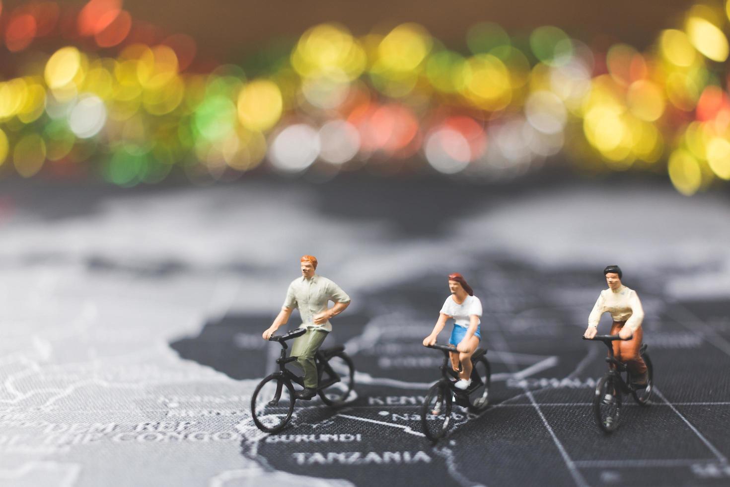 Miniature travelers riding a bicycle on a world map, traveling and exploring the world concept photo