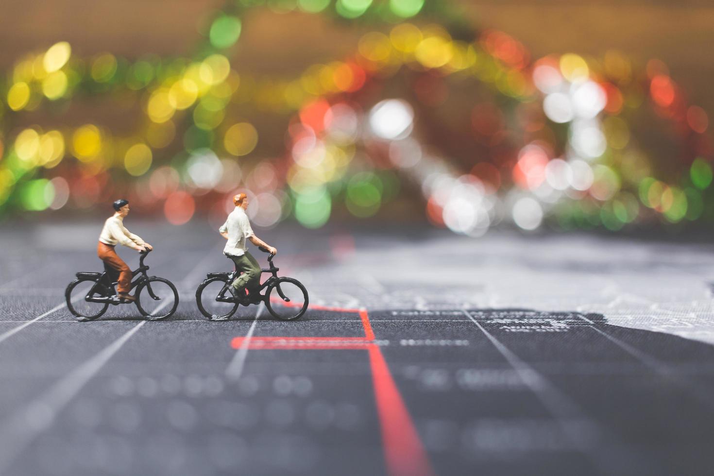 Miniature travelers riding a bicycle on a world map, traveling and exploring the world concept photo