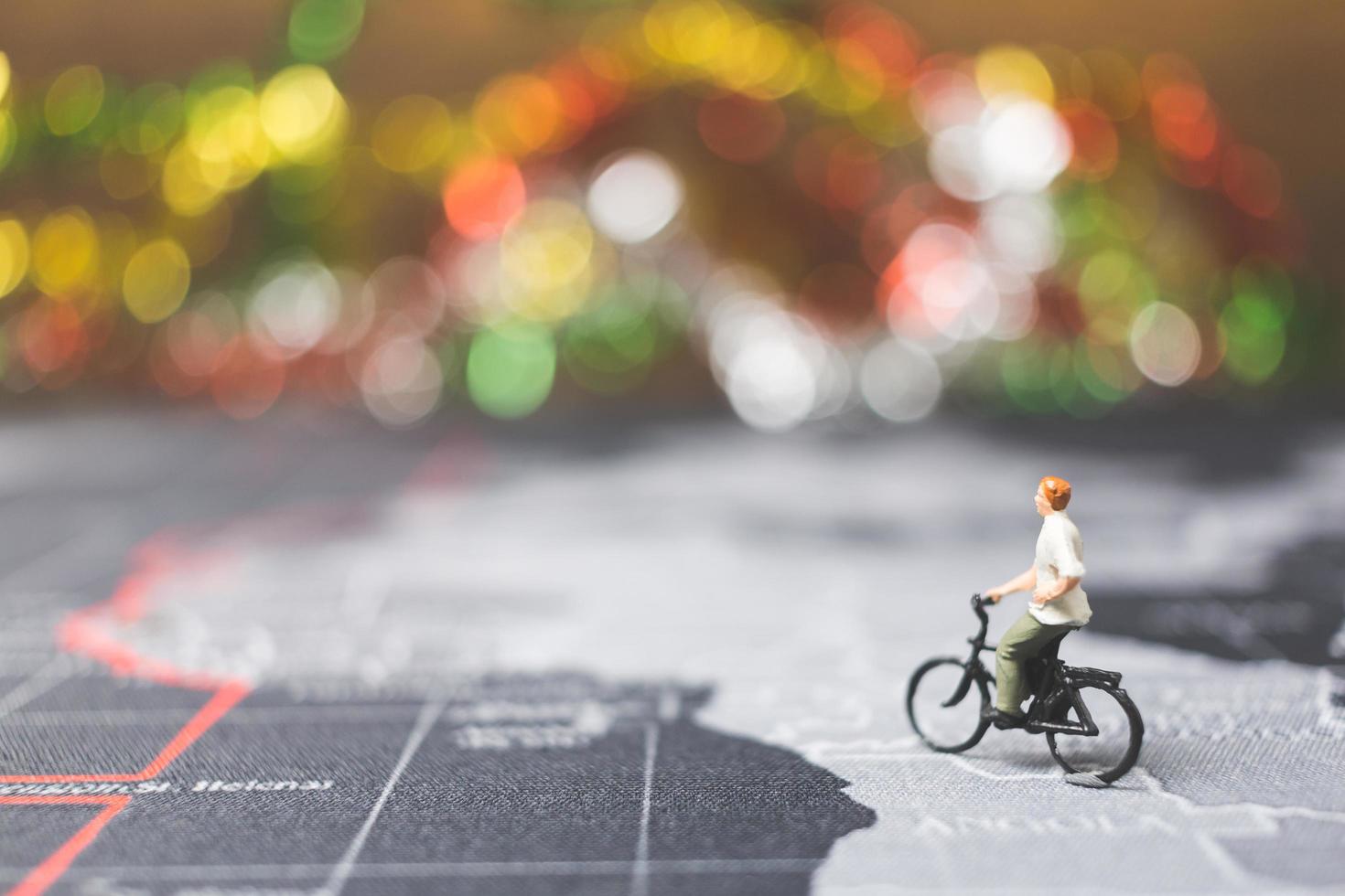 Viajero en miniatura montando una bicicleta en un mapa del mundo, viajando y explorando el concepto del mundo foto