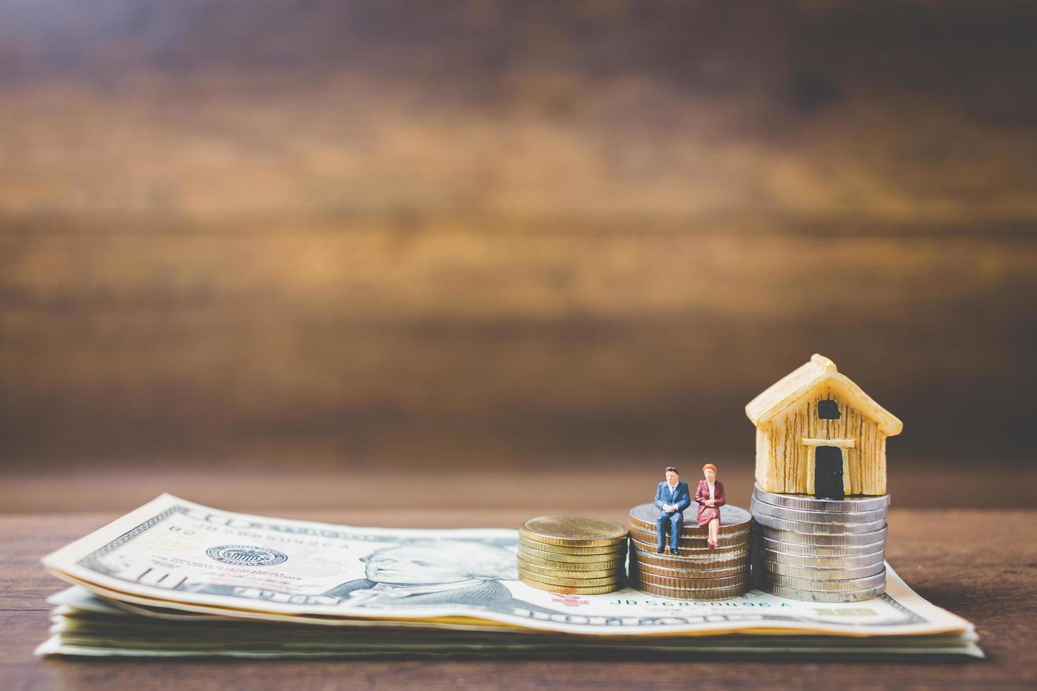 Miniature businessmen on money on a wooden background photo