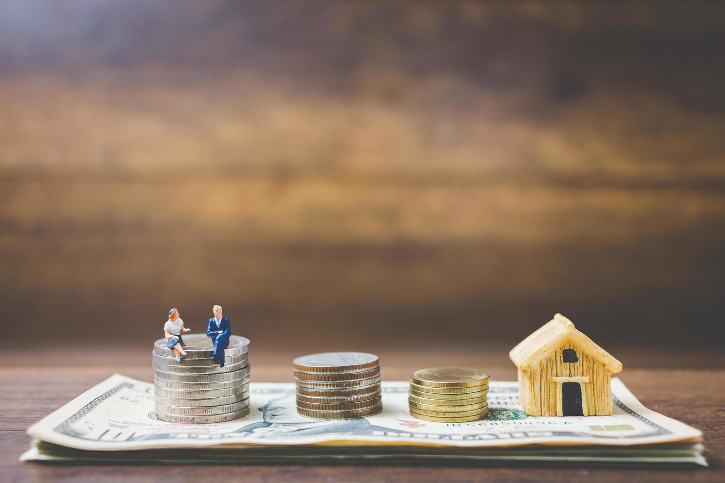 Miniature businessmen on money on a wooden background photo