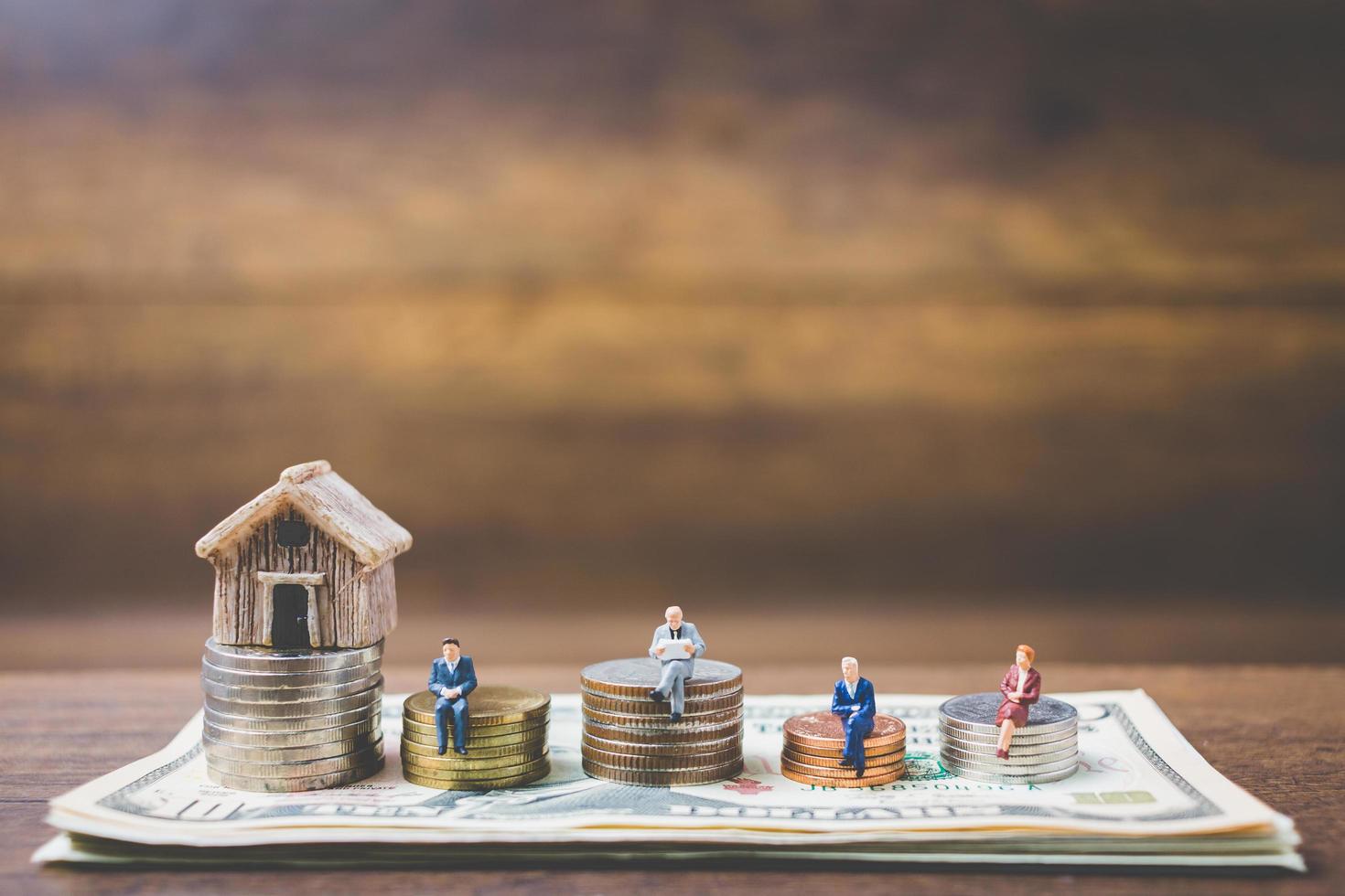 Miniature businessmen on money on a wooden background photo