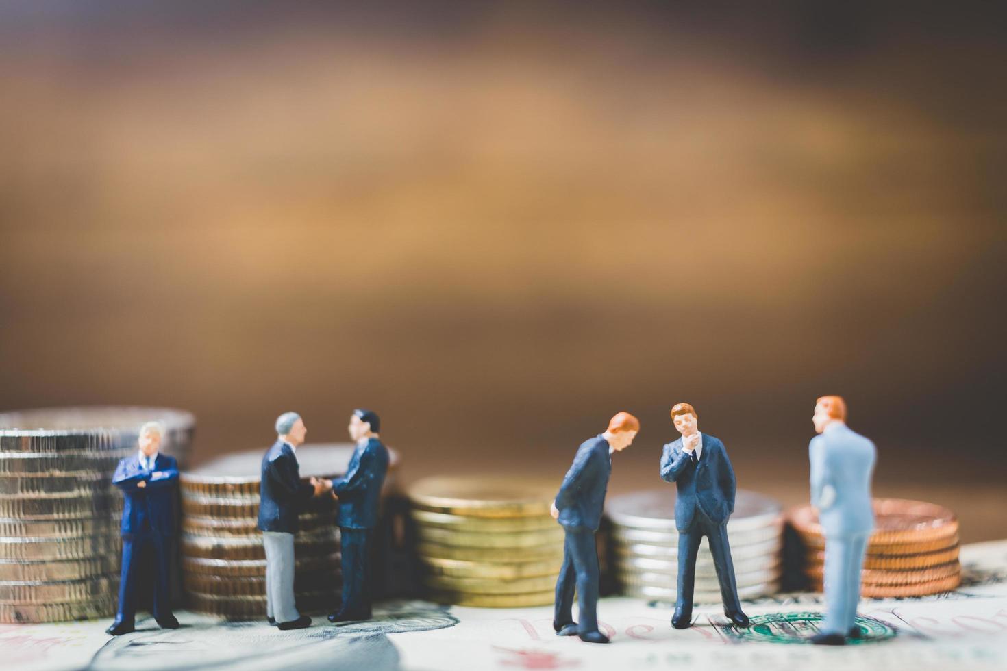 Miniature businessmen on money on a wooden background photo