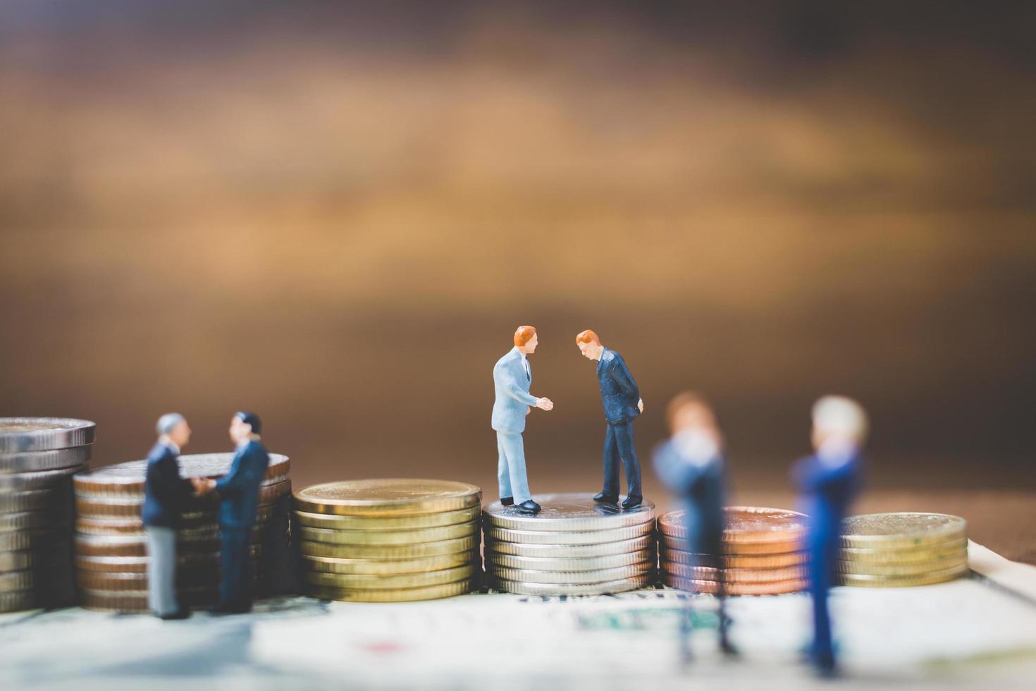 Miniature businessmen on money on a wooden background photo