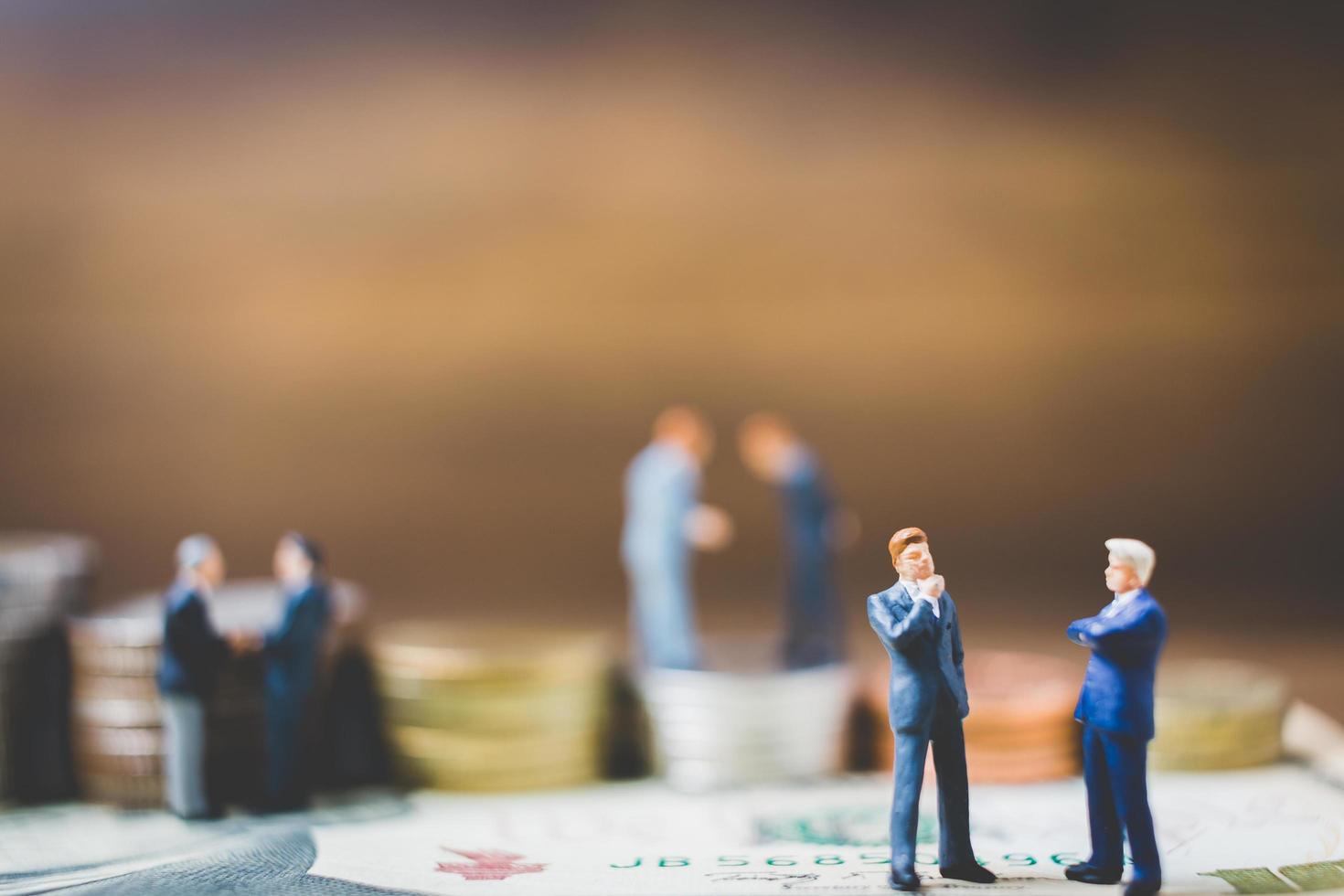 Miniature businessmen on money on a wooden background photo