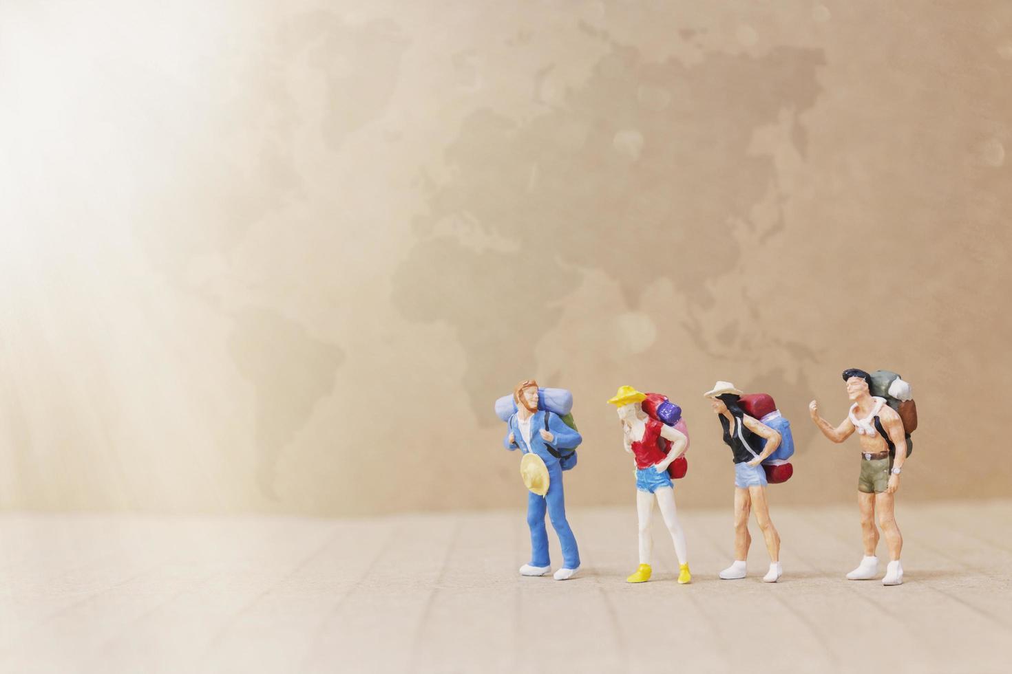 Miniature travelers with backpacks walking on a map, travel and adventure concept photo