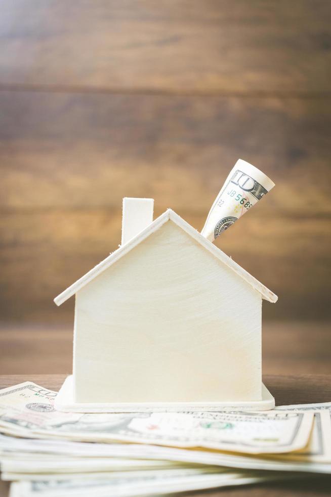 Money and house model on a wooden background, finance and banking concept photo
