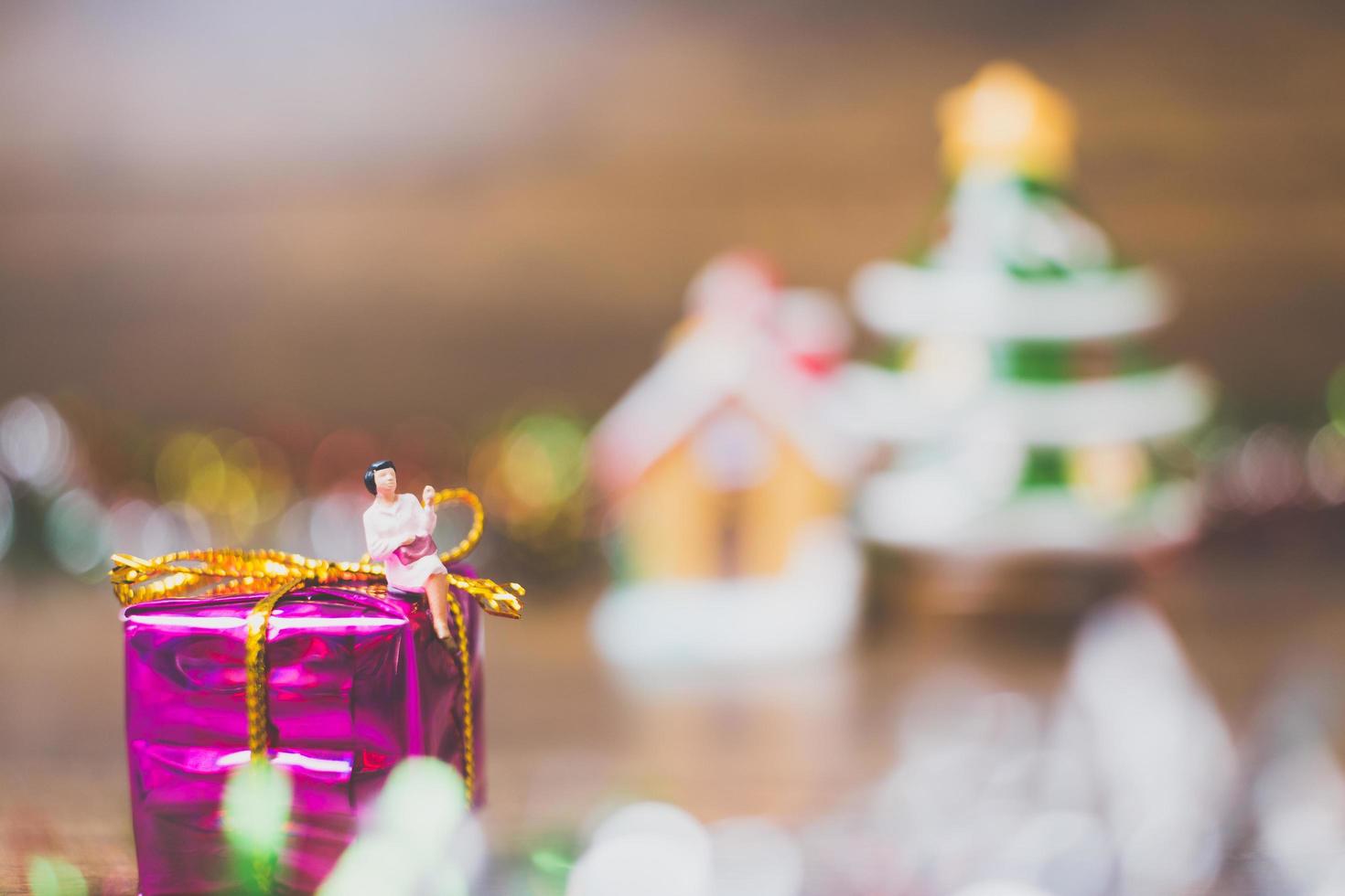 Persona en miniatura en una caja de regalo con decoración de celebración navideña en el fondo foto