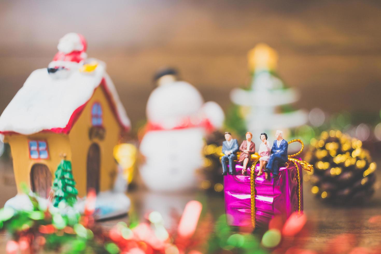 Gente en miniatura en una caja de regalo con decoración de celebración navideña en el fondo foto