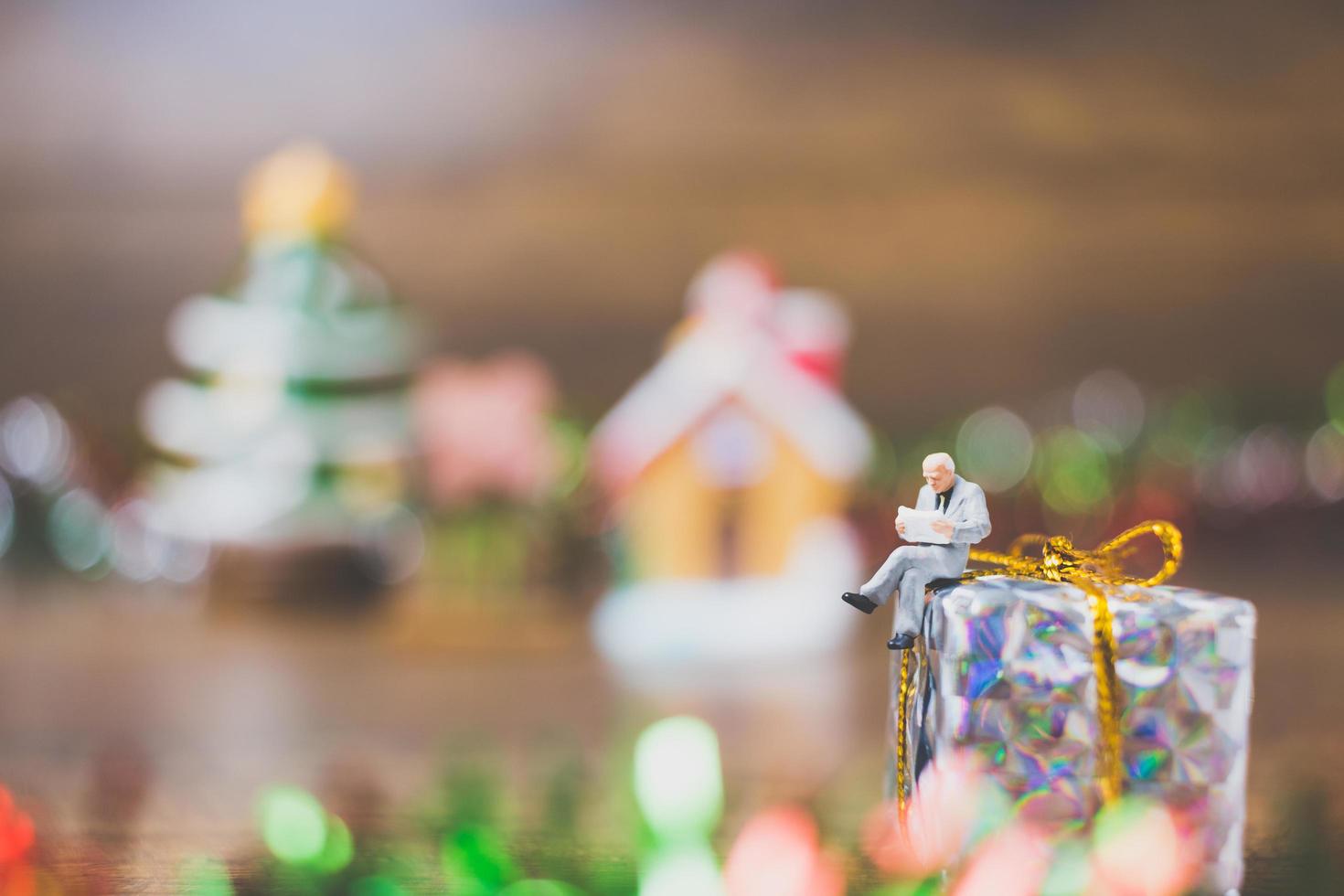 Persona en miniatura en una caja de regalo con decoración de celebración navideña en el fondo foto